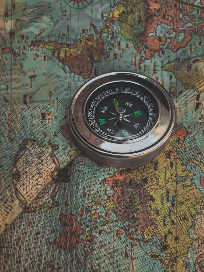 A metal compass resting on a vintage world map captures a sense of adventure and exploration.